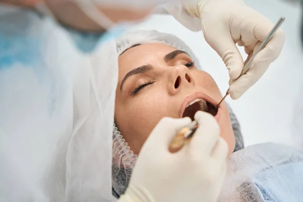 现代牙科诊所的医生为一位年轻妇女清洁牙槽 牙医使用特殊的工具 — 图库照片