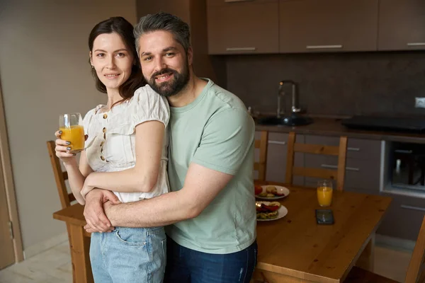 stock image Bearded husband and a sweet wife settled down at home in the kitchen, the man hugged his wife