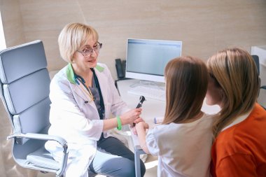 Pediyatri randevusunda kızıyla klinikte olan genç bir kadın, doktor kızla kurnaz bir şekilde iletişim kuruyor.