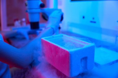 İş yerindeki laboratuvar çalışanı güçlü bir mikroskop ve sıvı nitrojen kullanıyor.