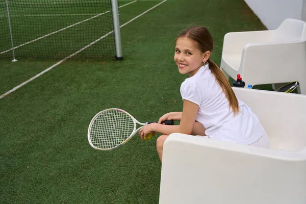 十代の少女はテニスコートのレクリエーションエリアで休んでいる 彼女は快適な椅子に座っています — ストック写真