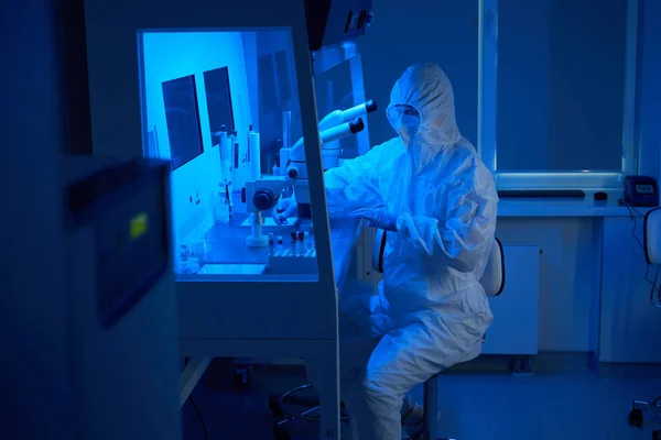 stock image Man in a sterile uniform uses a micromanipulator set , he also uses a powerful microscope