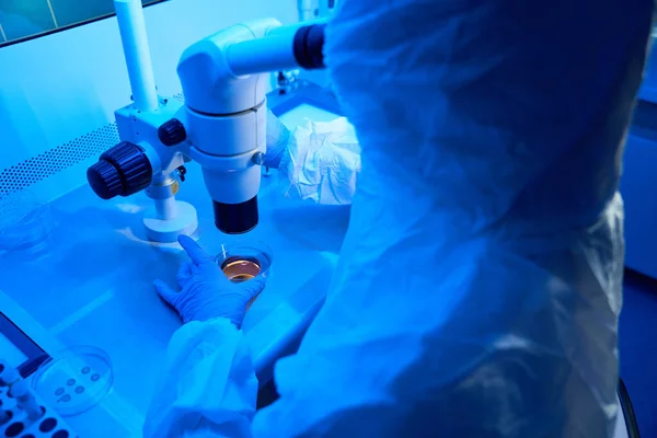 Laboratory employee in a sterile room performs a biopsy of embryos, he uses the micromanipulator set