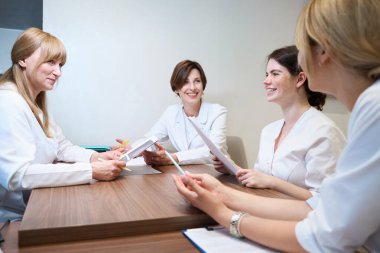 Tıbbi danışmanlık için toplanan üniformalı kadınlar ultrason taramalarını analiz ederler.