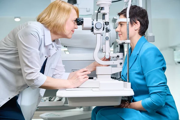 聚焦眼科医生通过缝隙灯显微镜观察女性患者的眼睛 — 图库照片