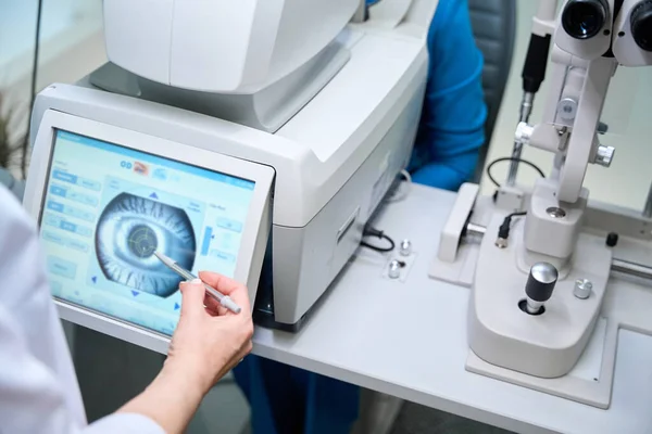 女性眼科医生在自动折射触摸屏上看成年人的眼睛图像 — 图库照片