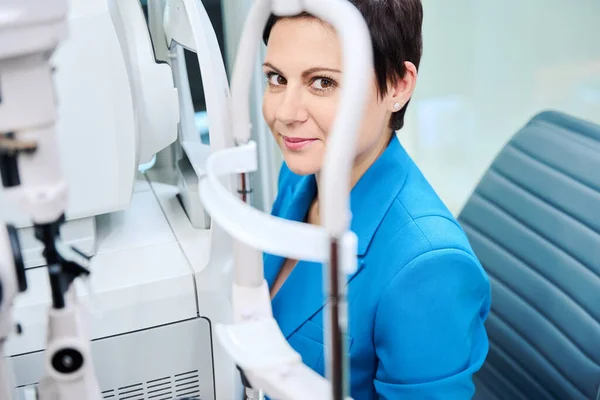眼科诊所眼科器械前静坐女性患者的画像 — 图库照片