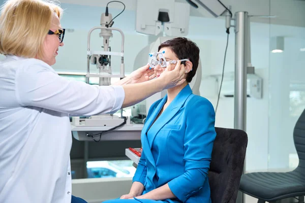 大人の女性の顧客の表面に試験レンズ フレームを置く集中された目の専門家 — ストック写真