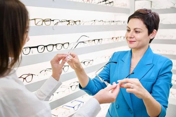 Zadowolona Klientka Biorąca Dwie Pary Okularów Bez Obręczy Rąk Optyczki — Zdjęcie stockowe