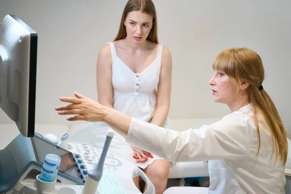 Frustrated Young Woman Sitting Couch Ultrasound Room Female Doctor Points — Stock Photo, Image