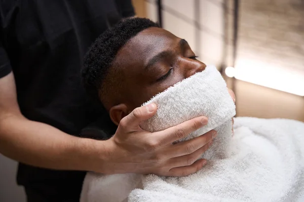 Barber Put Warm Towel Face African American Guy Client Sits — Stock Photo, Image