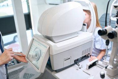 Klinikteki otorraktometri sırasında çocuk gözlerindeki ışık kırılmasını inceleyen deneyimli göz doktoru.