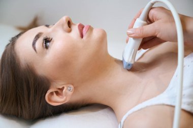 Tiroit ultrasonu uygulanan genç bir kadın, hasta standart bir muayeneden geçiyor.