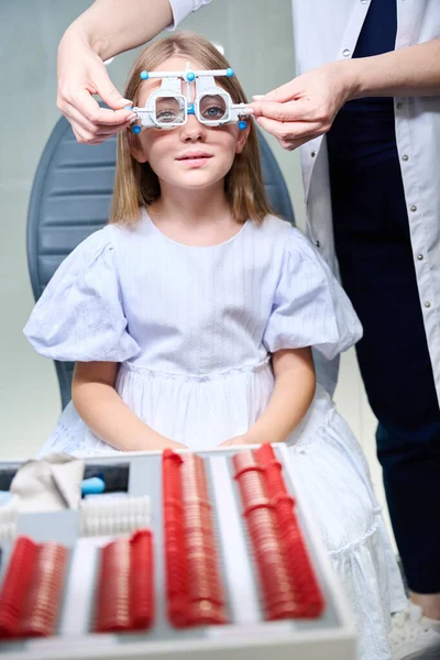 検査椅子に座っている子供は光学試験フレームの偏光フィルターを彼女の顔に取り付けている間 — ストック写真
