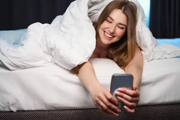 Mulher Feliz Coberto Com Cobertor Telefone Celular Navegação Enquanto Deitado — Fotografia de Stock