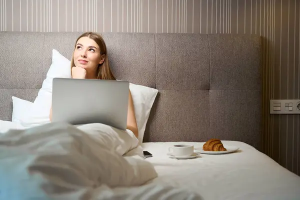 Vonzó Takaróval Borított Néz Félre Használja Laptop Miközben Feküdt Ágyban — Stock Fotó