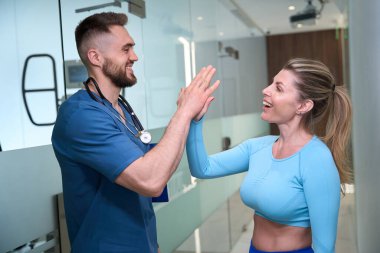 Mutlu terapist ve rehabilitasyon uzmanı beşlik çakıyor, insanların tekrar yürümesine yardım ediyor, rehabilitasyon merkezi