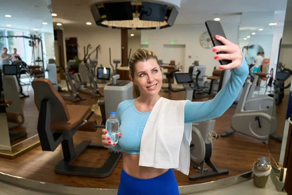 迷人的女运动员喝水 在智能手机上自拍 做完热身运动 做完体操背景 — 图库照片