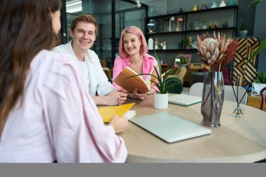 Yönetici müşterilerle iletişim kurar ve kataloglara bakar, yuvarlak bir masada otururlar.