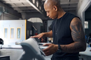 Kurulum ve araba imalatından önce zımparalama ve bitirme kalitesini kontrol eden odaklı Afrikalı Amerikalı adam