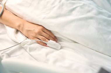 Yüzük parmağında teşhis sensörü olan bir kadın eli, hastanın hayati fonksiyonlarını izlemek için ekipman kullanılır.