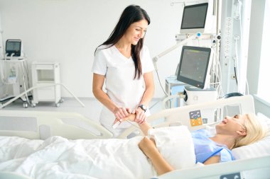 Doktor, ameliyattan sonra bayanı cesaretlendirir. Kadın hastaların elini tutar.