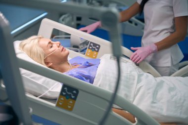 Doktor ameliyattan sonra hastaların kan basıncını ölçer, doktor koruyucu eldiven giyer.