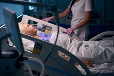 Doktor ameliyattan sonra hastanın durumunu kontrol eder. Doktor koruyucu eldiven giyer.