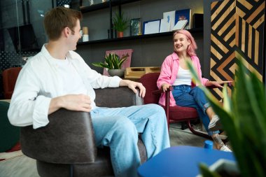 Gülümseyen sevgili ve sevgili rahat koltuklarda oturuyor, ev için mobilya seçiyorlar.