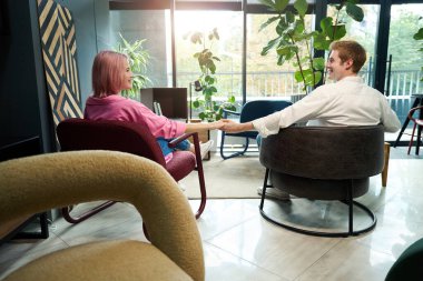 Mutlu sevgili ve sevgili rahat koltuklarda oturuyor, el ele tutuşuyorlar.