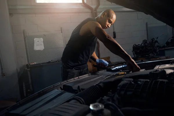 油とガラスの洗濯機のレベルをチェックする集中的なアフリカ系アメリカ人男性 車の修理 男性の趣味 自動車サービスステーションで時間を過ごす — ストック写真