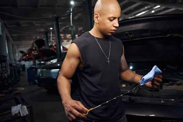 Seriöse Afroamerikanische Automechaniker Wischen Spezialmessgerät Das Niveau Von Motoröl Und — Stockfoto