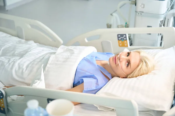 手術後の美しい女性は 患者の重要な機能を監視するための近代的な機器を備えた部屋にあります — ストック写真