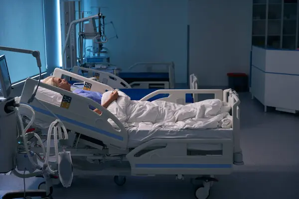 回復女性は集中治療室の術後ベッドに横たわり 彼女は医療機器に接続されています — ストック写真