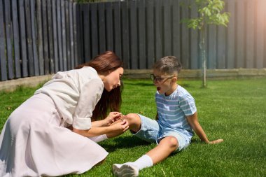 Bakıcı anne oğullarının dizindeki yarayı alçıyla kapatıyor, çocuk acı çekiyor ve ağlıyor.