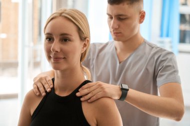 Bir masörle konsültasyon yapan genç bir bayan. İçeride çok fazla güneş ışığı var.