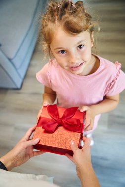 Anne küçük tatlı kızına kırmızı hediye kutusu veriyor, tatilini kutluyor güzel doğum günü kızıyla.