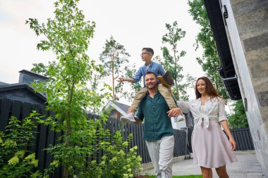 Beyzbol eldivenli çocuk babasının omuzlarında, mutlu annesinin yanında oturuyor.