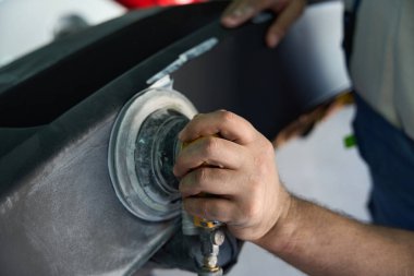 Erkek işçilerin yakın çekimleri araba gövde panelini yörünge cilasıyla cilalıyor