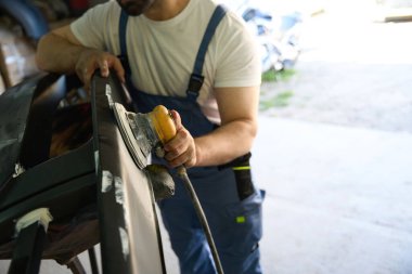 Araba tamircisinin araba tamponunu cilalarken yörünge cilası kullanırken çekilmiş fotoğrafı.