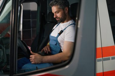 Müşteri aracında otururken laptop ekranına bakan odaklanmış otomotiv teknisyeni