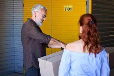 Karton kutulara bir şeyler koyar, erkek bant kesicisi kullanır.