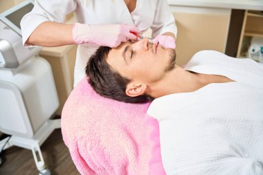 Estetik tıp kliniğinde plasmolift seansına katılan doktor koruyucu eldivenlerle çalışır.