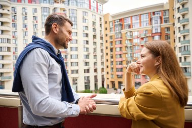 Yöneticiler, kadın ve erkek büyük bir ofis binasının balkonunda iletişim kuruyor, rahat kıyafetler giyen insanlar...