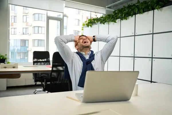 Emotional Man Laptop Sits Large Office Table Storage Cabinets Nearby — Stock Photo, Image