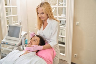 Doktor estetisyen hastaların yüzüne işaretler koyar. Bir kadın özel bir kalem kullanır.