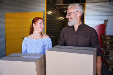 Gülen çift karton kutular taşıyor, insanlar depoda.