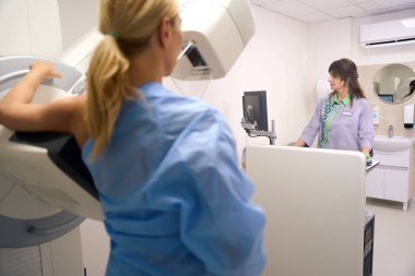 mammograf tarafından kontrol konsolu ile yönetilen mammografi makinesi üzerinde dijital meme tomozeni uygulanan hasta