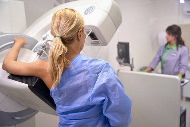 mammografi ünitesinde kontrol konsolu aracılığıyla radyograf tarafından yönetilen 3D mammograma maruz kalan kadının arka görüntüsü