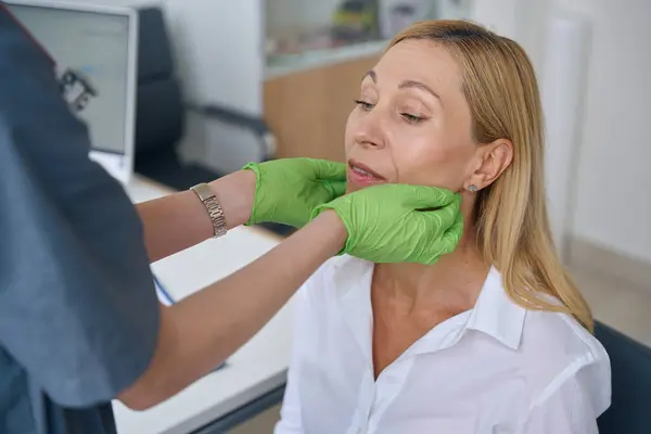 身体検査中に女性患者の唾液腺をパラパスする手袋でEnt医師の手 — ストック写真
